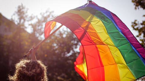 Frau weht Regenbogenflagge durch die Luft