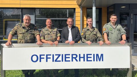 Vier Bundeswehrsoldaten und Finanzminister Lorz stehen hinter dem Gebäudeschild mit der Aufschrift "Offizierheim"