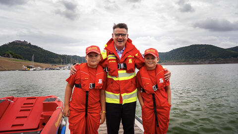 Ein mann und zwei Kinder stehen vor einem See.