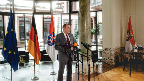 Finanzminister Alexander Lorz steht vor Mikrofonen in einer Interviewsituation.