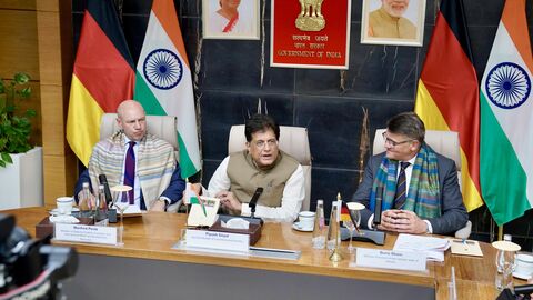 Staatsminister Pentz, indische Minister Piyush Goyal und Ministerpräsident Rhein sitzen nebeneinander an einem Tisch. Im Hintergrund stehen deutsche und indische Flaggen.