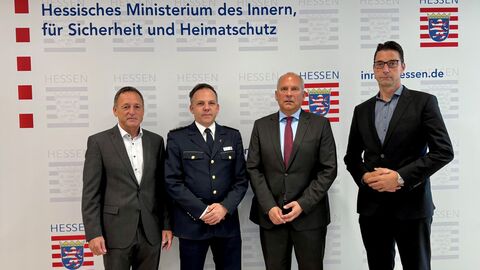 Vier Männer stehen in Anzügen nebeneinander.