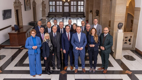 Mehrere Menschen stehen in einer Halle nebeneinander.