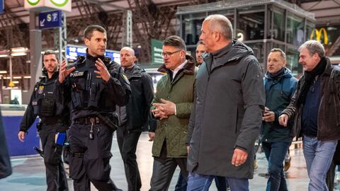 Ministerpräsident und Innenminister gehen gemeinsam mit Polizisten durch einen Bahnhof